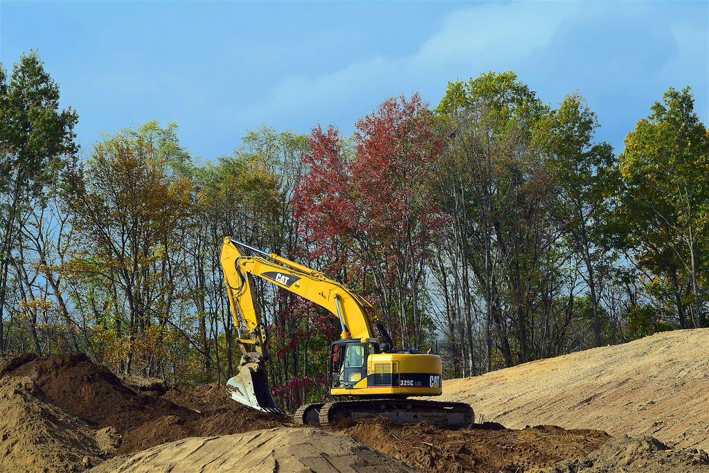 Excavator preparing earth on a wooded homesite