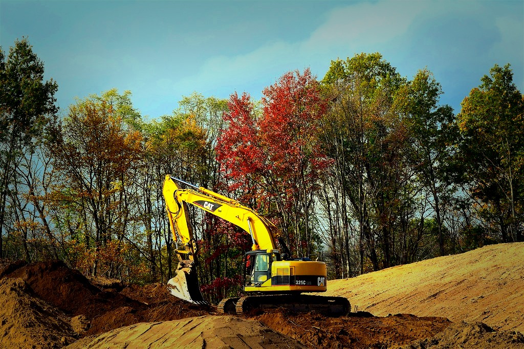 Excavator digging earth on a wooded rural jobsite
