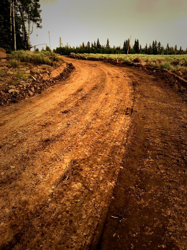 Freshly graded gravel access road through mountain terrain